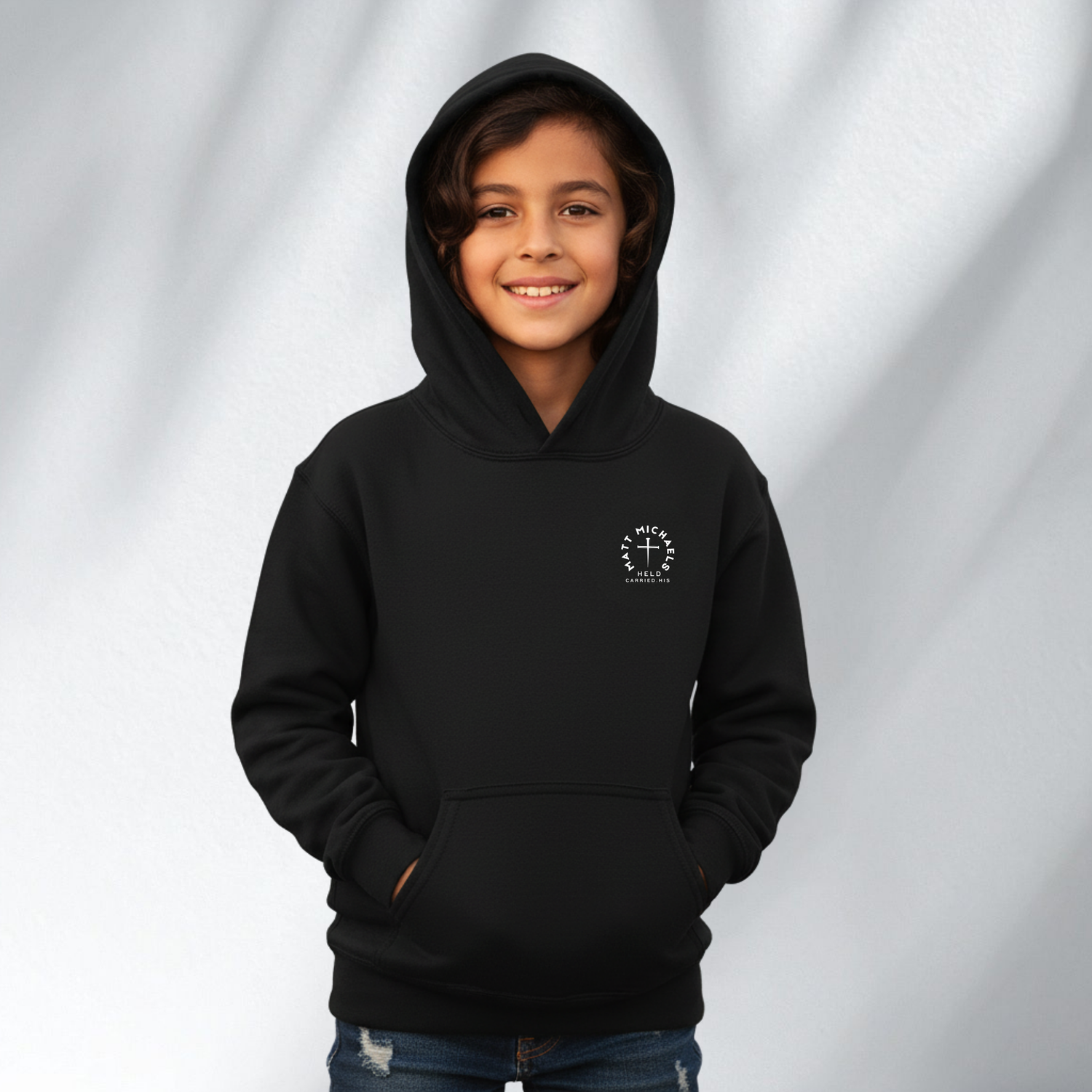 Child wearing a black Matt Michaels hoodie with hood up, youth collection